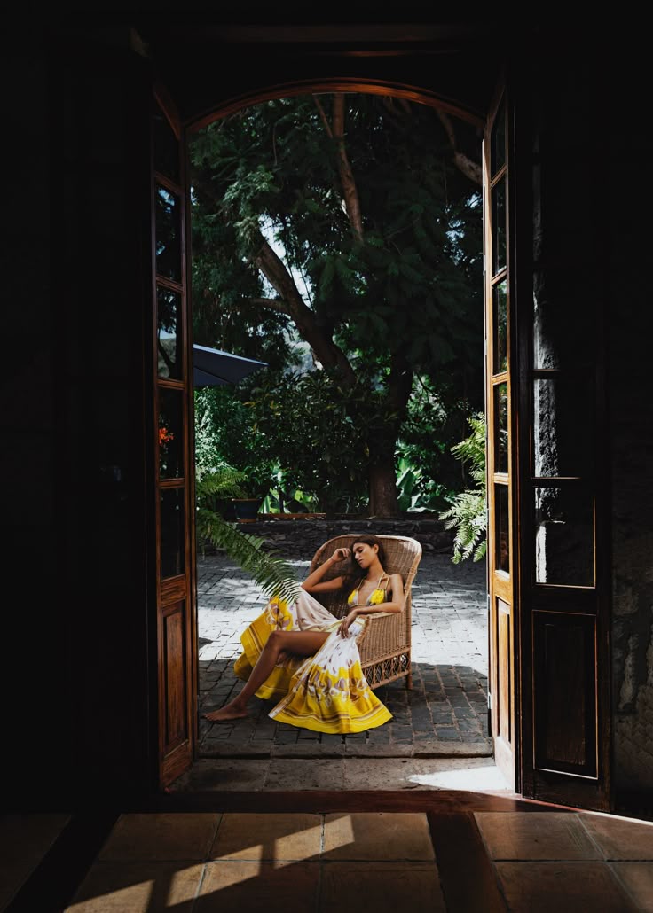 Woman relaxing in wicker chair in tropical courtyard